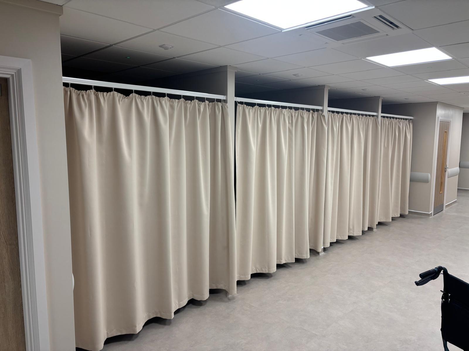 Care home assessment area with cream cubicle curtains on aluminium track