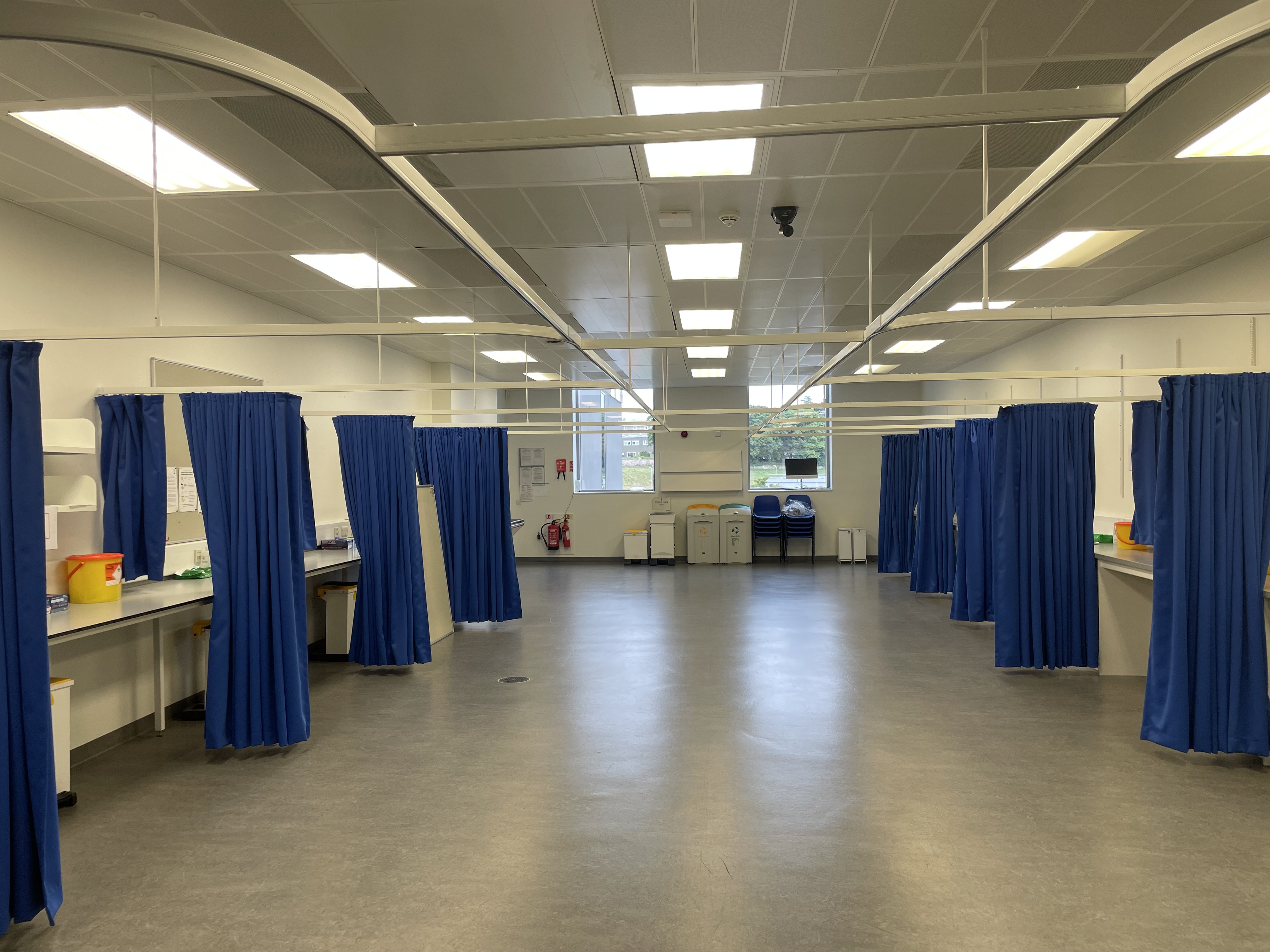 Multi-bay treatment room with curved cubicle tracks and blue curtains